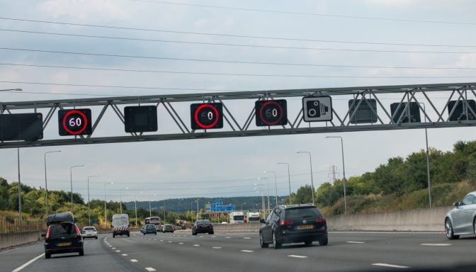 A smart motorway in the UK, which has four lanes. The image is taken from a passenger's perspective, and shows that the speed limit has been reduced to 60mph in all lanes.