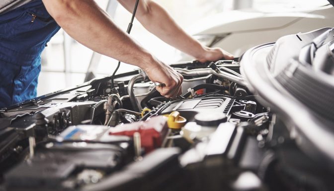 A close-up shot of a mechanic's hands working on a car engine.