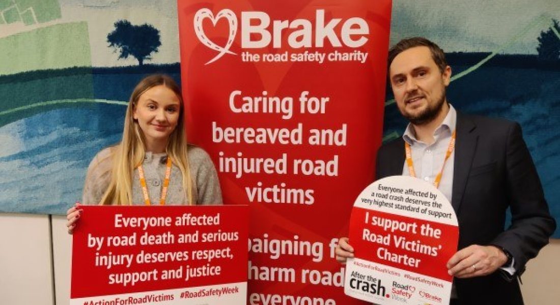 Road victim Scarlett Cottlee stands with a colleague whilst holding a Road Safety Week poster.