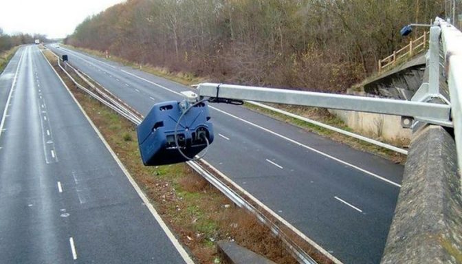 A close-up image of a traffic camera, mounted above a dual carriageway in the UK.