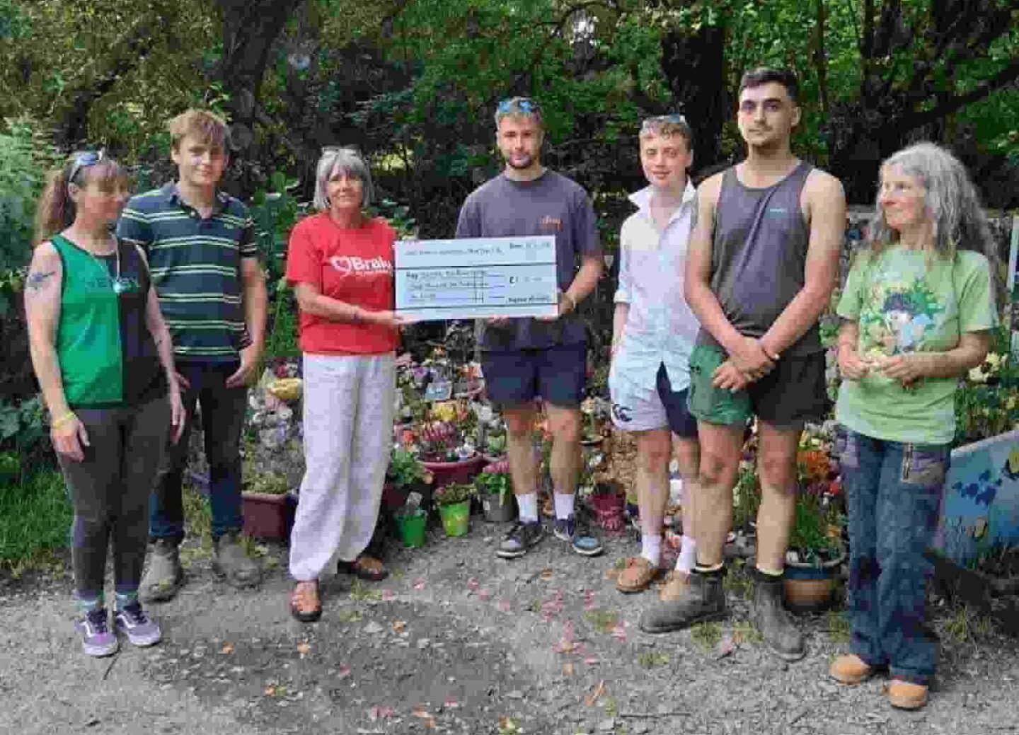 A group of people pose for a photograph at a charity cheque presentation.