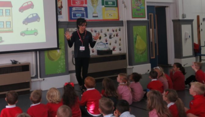 A woman delivers a road safety presentation to a class of children.