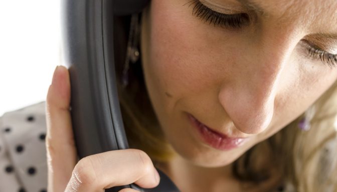 A woman talking on her phone, with a thoughtful expression on her face.