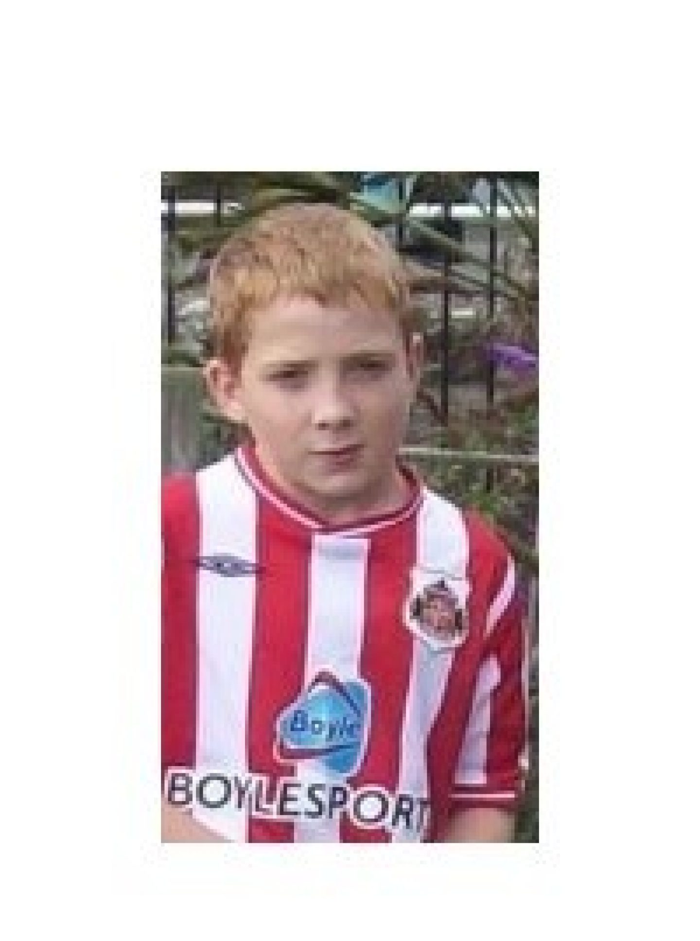 A young boy wearing a football jersey poses for a photo.