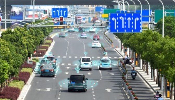 A road with vehicles, some of which are highlighted with blue digital overlays, suggesting the concept of autonomous or self-driving vehicles and the technology involved in their operation.